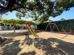 写真：ひばり児童公園の遊具（すべり台・ブランコ）と大きなクスノキ